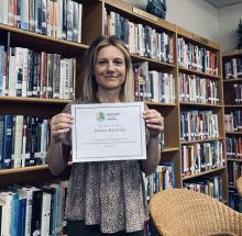 Joanna McCloskey in her library with her certificate.